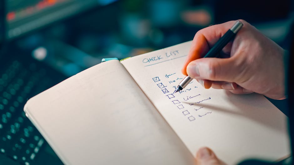 A close-up of a person holding a black marker and checking off items on a checklist titled 'Check Out' written in black ink on a white, graph paper notebook. The checklist includes boxes next to tasks